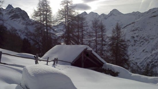 Cabane enneigée dans un paysage de montagne hivernal.