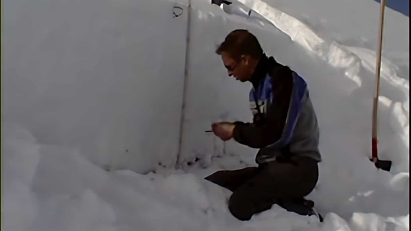 Homme agenouillé dans la neige, réalisant un profil nivologique.