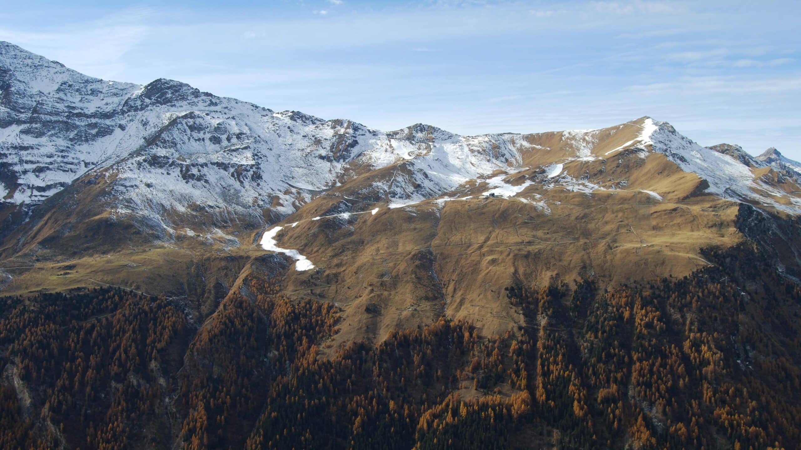 Montagnes enneigées, forêt d'automne et ciel bleu.
