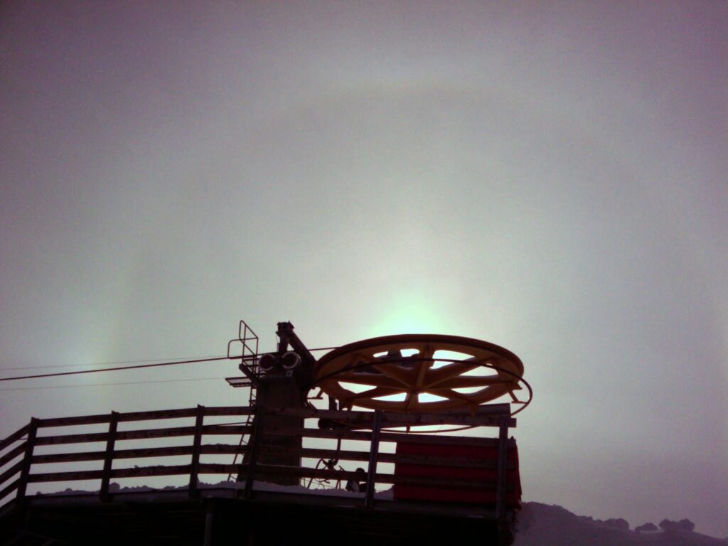 Vue de la roue de renvoi du télésiège de la Corne de Sorebois, avec un halo lumineux dans le ciel nuageux.