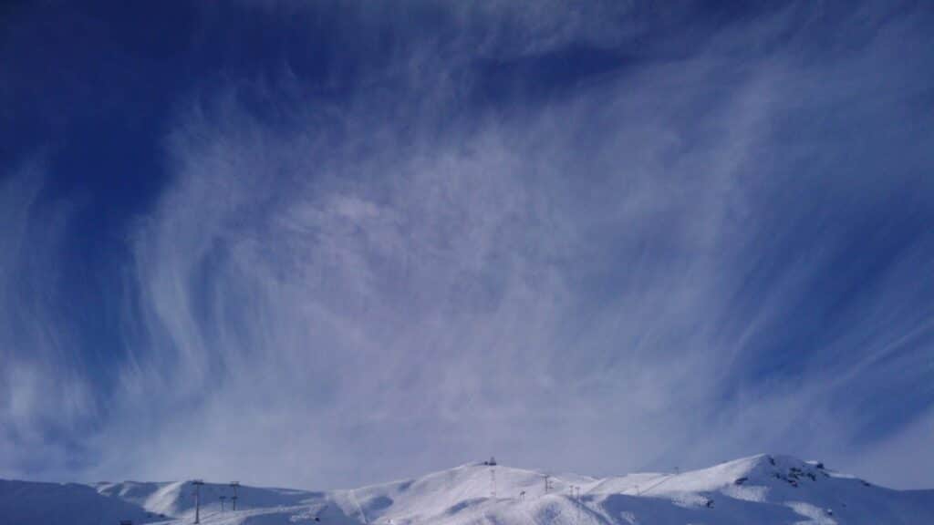 Ciel bleu avec de jolis cirrus au-dessus de montagnes enneigées.