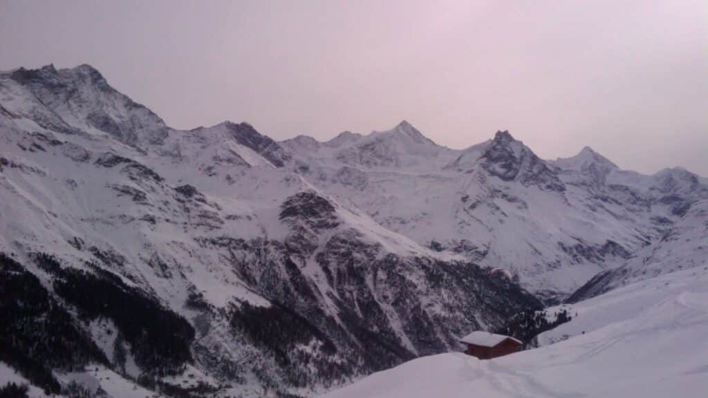 Panoramic view of snow-covered mountains under a cloudy sky.