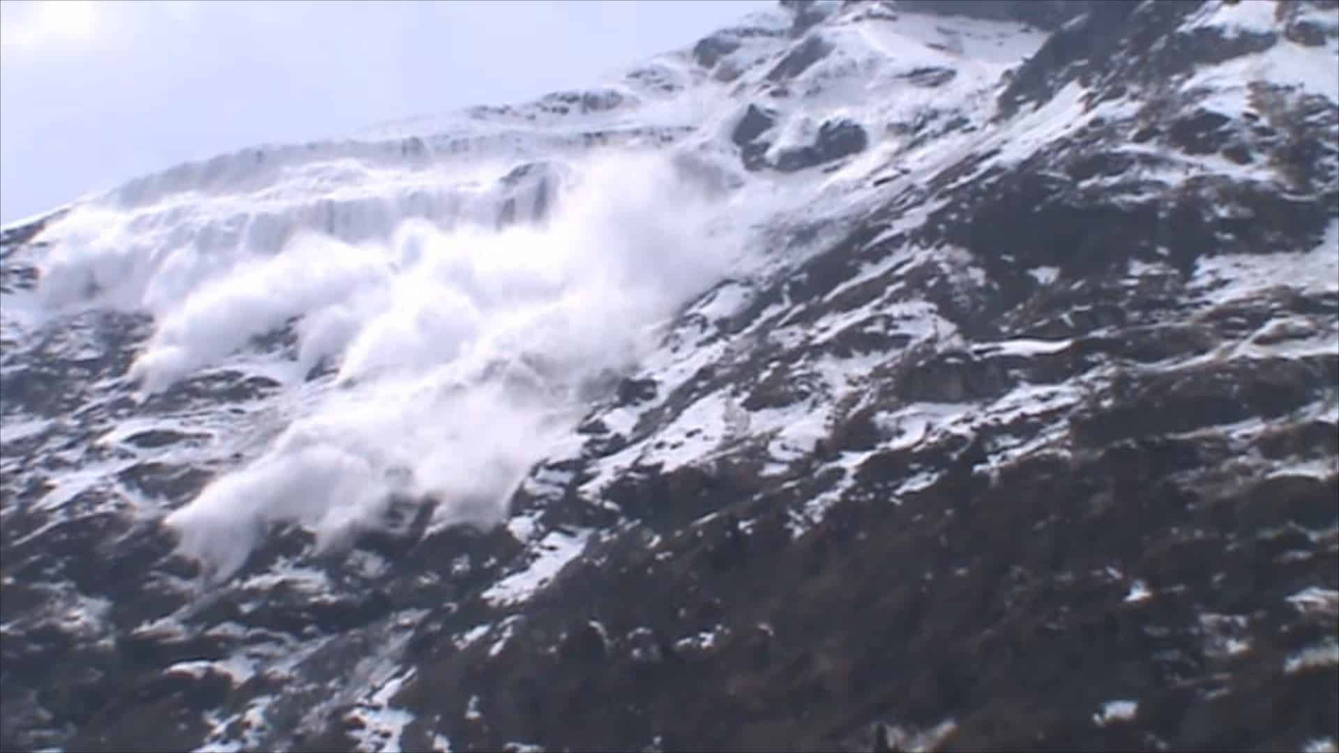 Grande avalanche de neige dévalant une montagne enneigée.