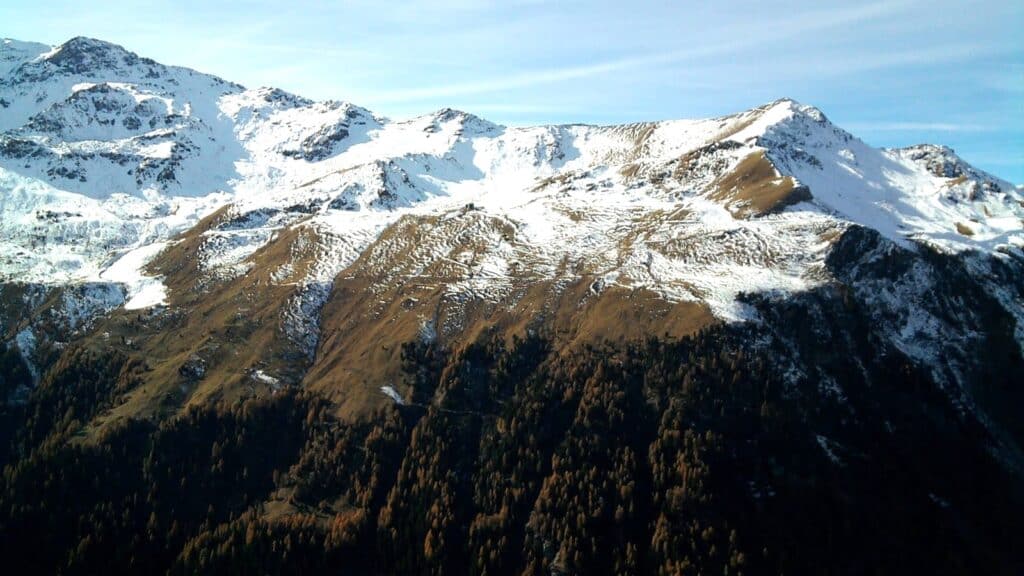 Vue d'une montagne enneigée avec des pentes dégagées et un ciel bleu en arrière-plan, illustrant les conditions météorologiques en novembre.