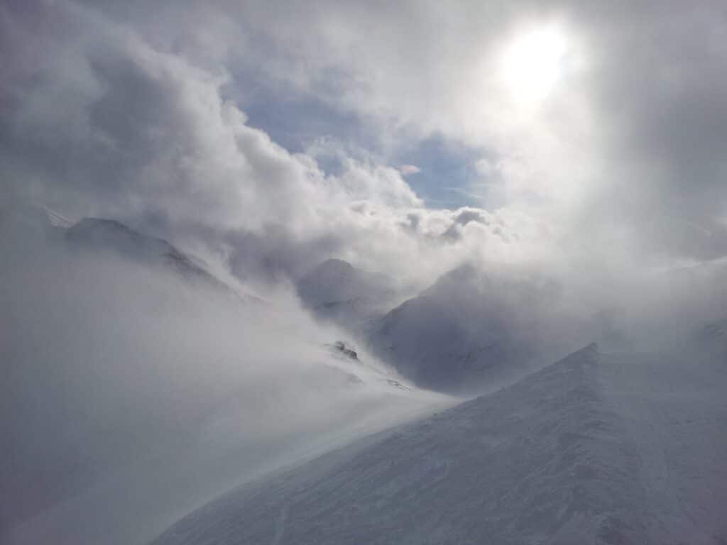 Vue panoramique des montagnes avec des nuages et de la neige visible, capturée au sommet de la Corne, dégageant une atmosphère hivernale et remplies de conditions de neiges récentes.