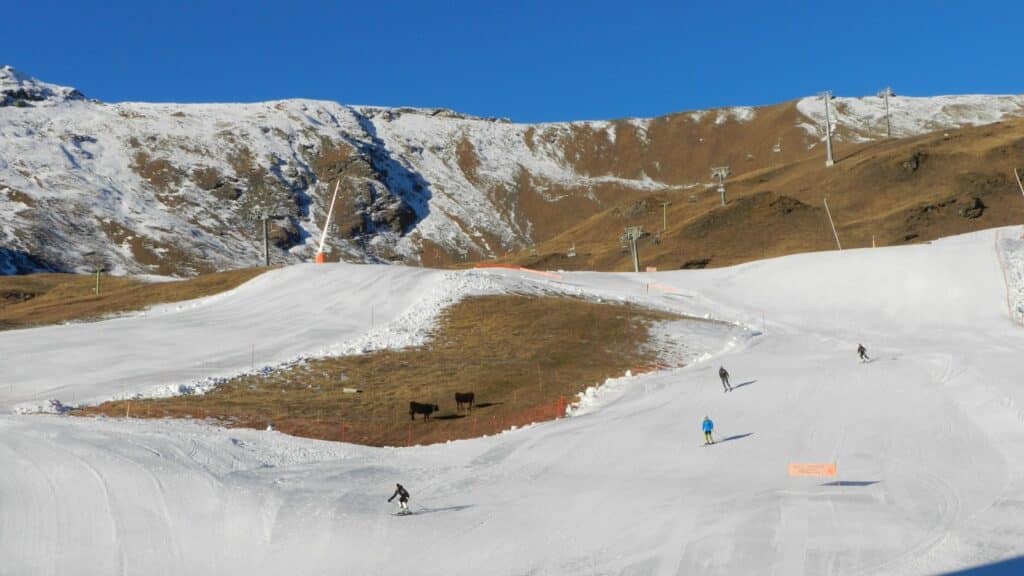 Piste de ski avec de la neige et des skieurs, montagnes en arrière-plan.