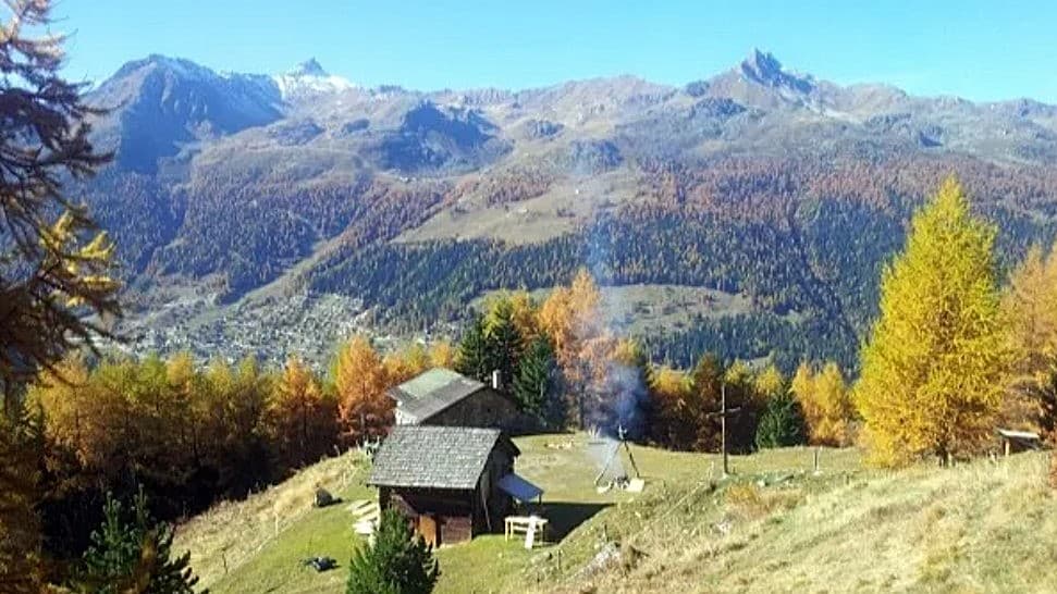 Chalets en montagne, forêt automnale, feu de camp et sommets.