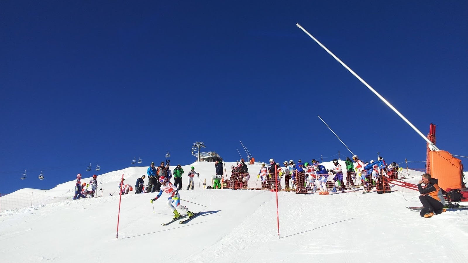 Skieur de slalom en pleine action sur piste enneigée sous ciel bleu.