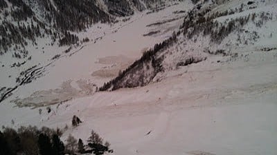 Vaste paysage montagneux enneigé avec vallée et traces d'avalanche.