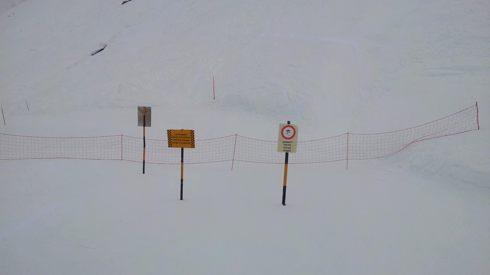 Piste de ski fermée pour risque d'avalanche avec filet de sécurité.