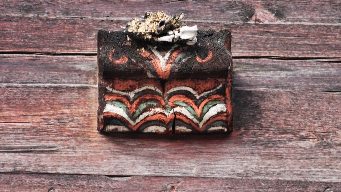 Bloc de bois peint aux motifs colorés sur mur rustique.