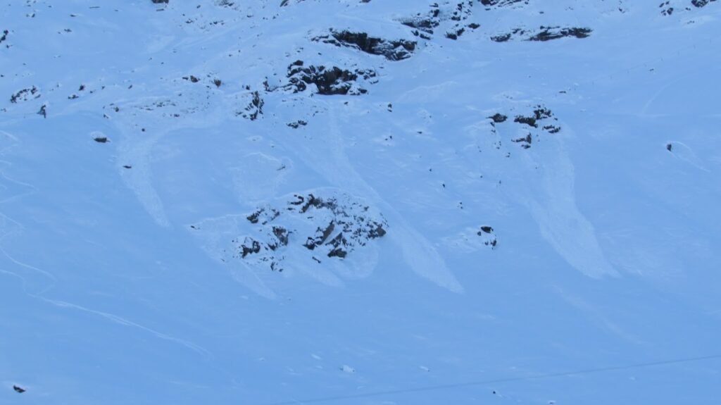 Rochers partiellement recouverts de neige, avec des traces visibles sur la surface, sous l'arête des 'Valentines' à Durand.