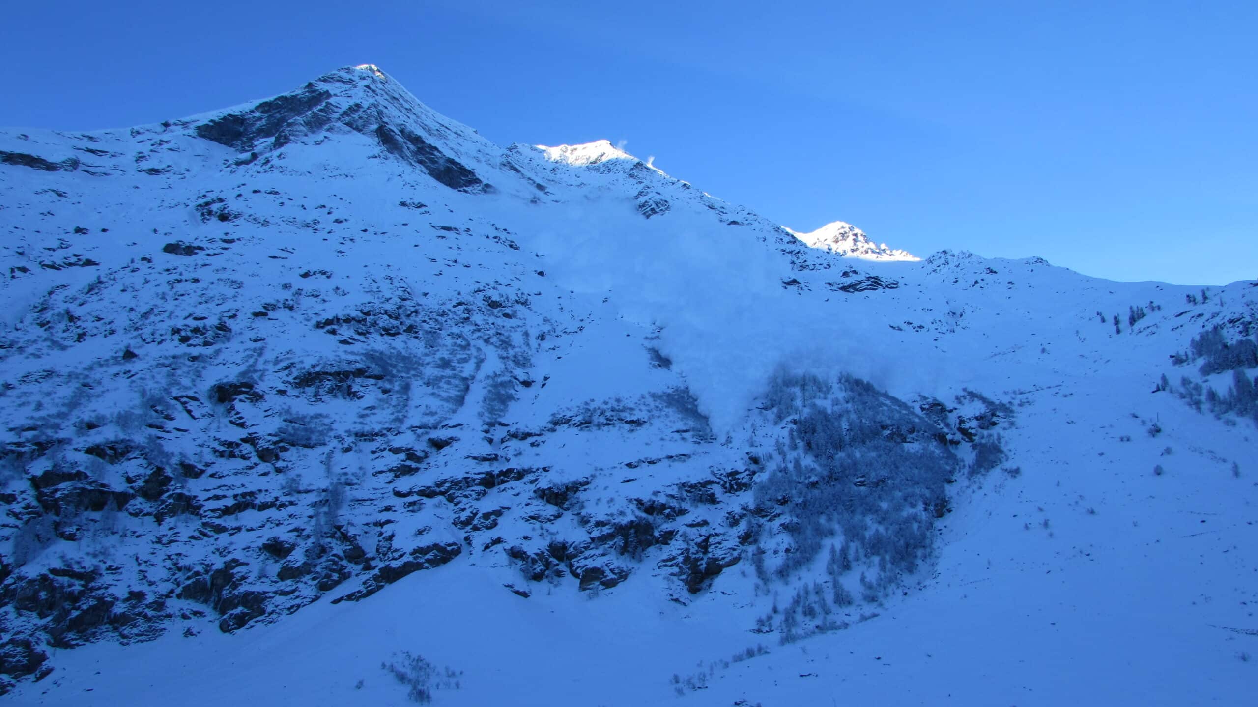 Une avalanche spectaculaire descend une pente de montagne enneigée.