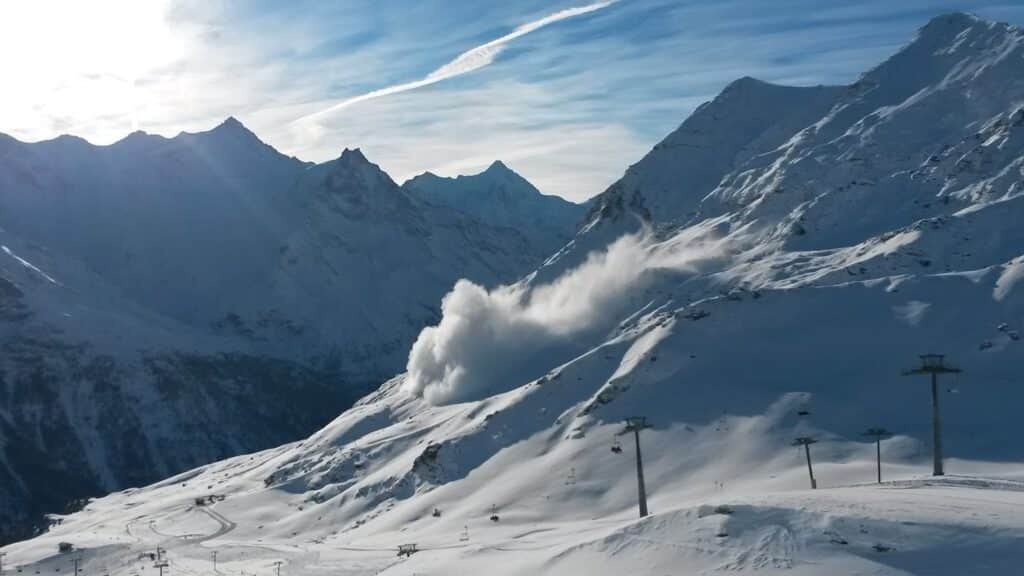 Vue panoramique d'une chaîne de montagnes enneigées avec une avalanche se déclenchant sur une pente.