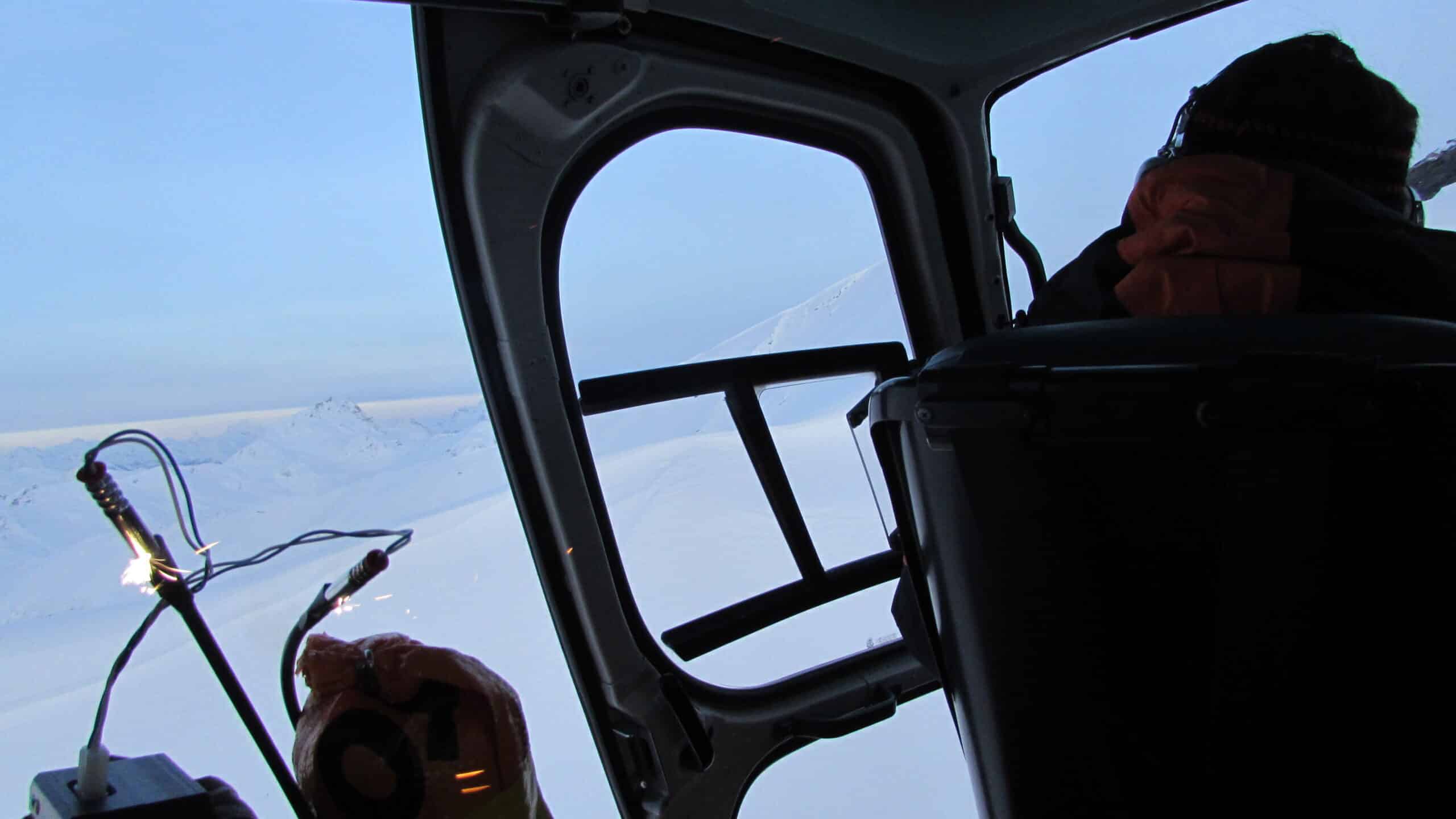 Montagnes enneigées vues d'un hélicoptère, avec étincelles d'équipement.