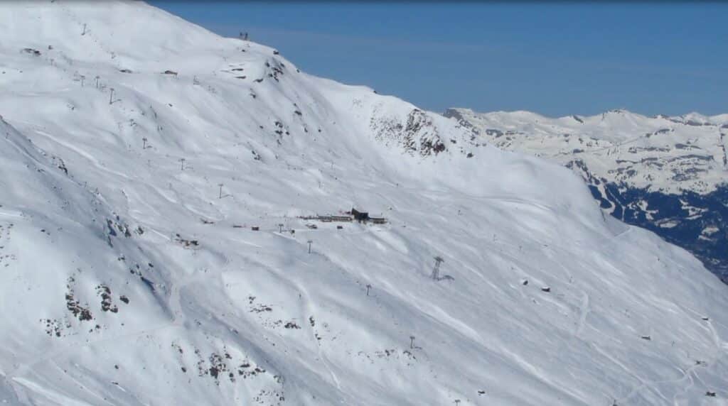 Vue panoramique du domaine skiable de Sorebois, recouvert de neige, avec des pistes et des remontées mécaniques visibles, sous un ciel bleu clair.