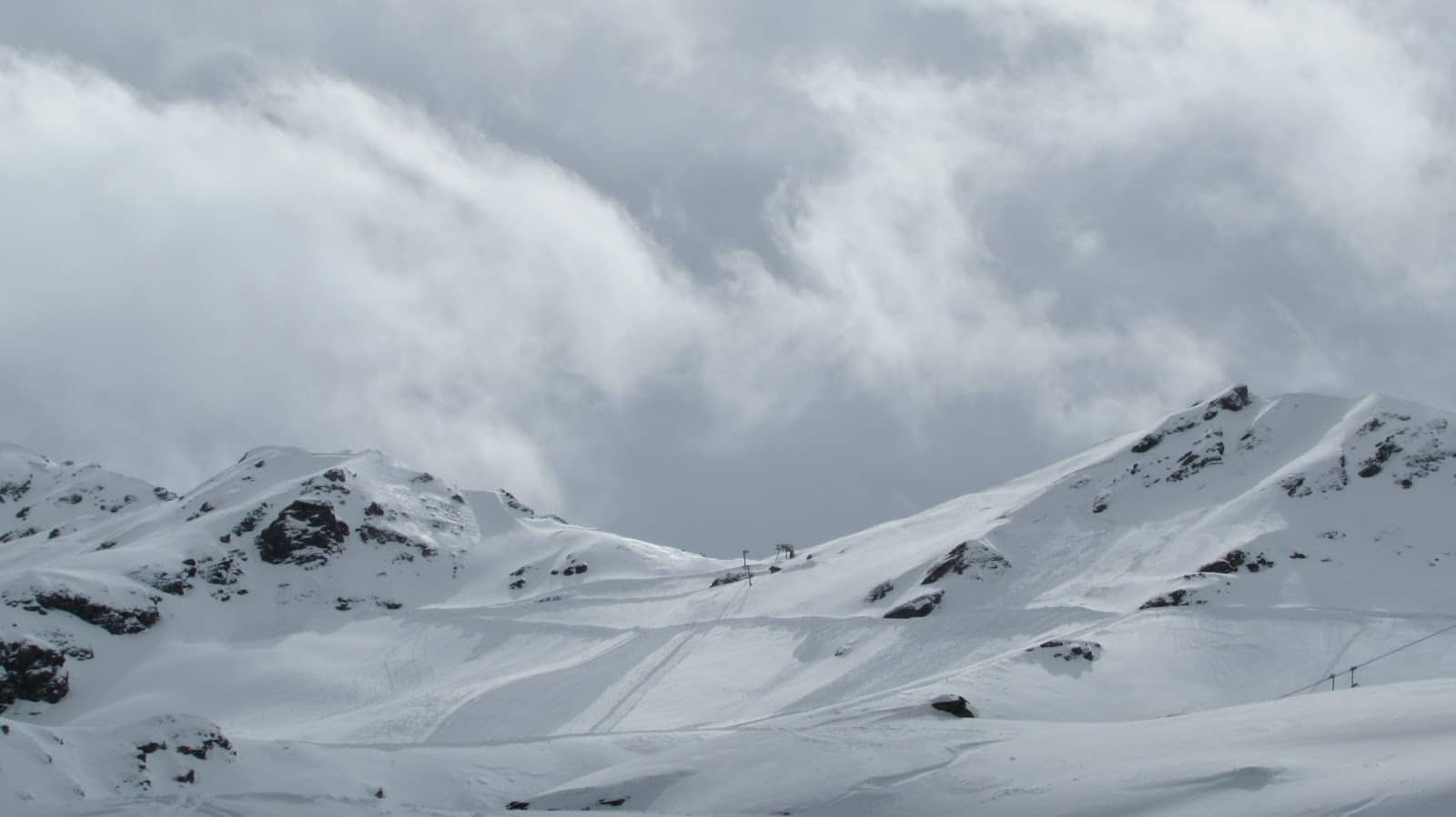 Pistes de ski enneigées sous un ciel couvert, remontées mécaniques visibles.