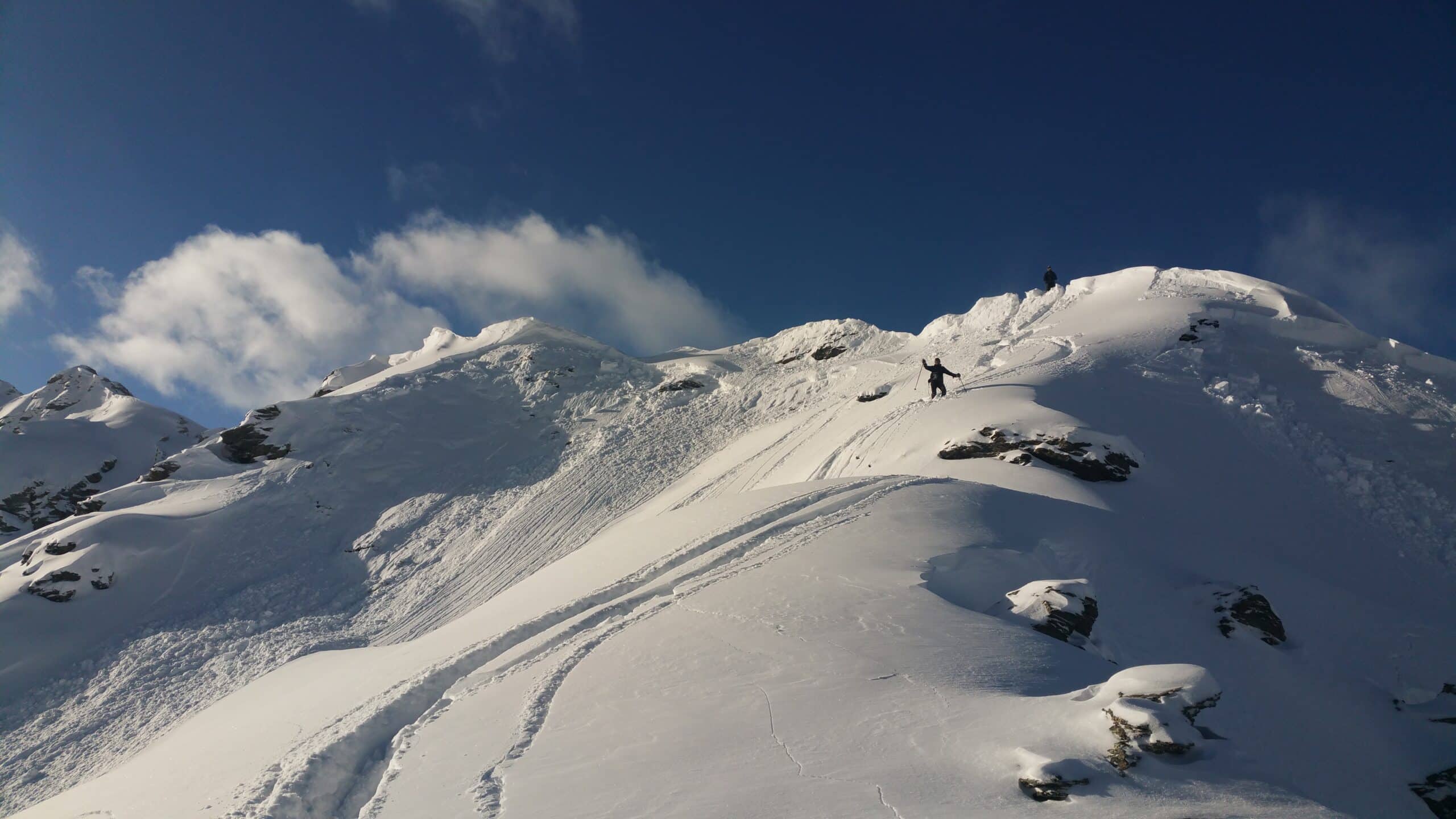 Ski de randonnée en montagne enneigée sous un ciel bleu.