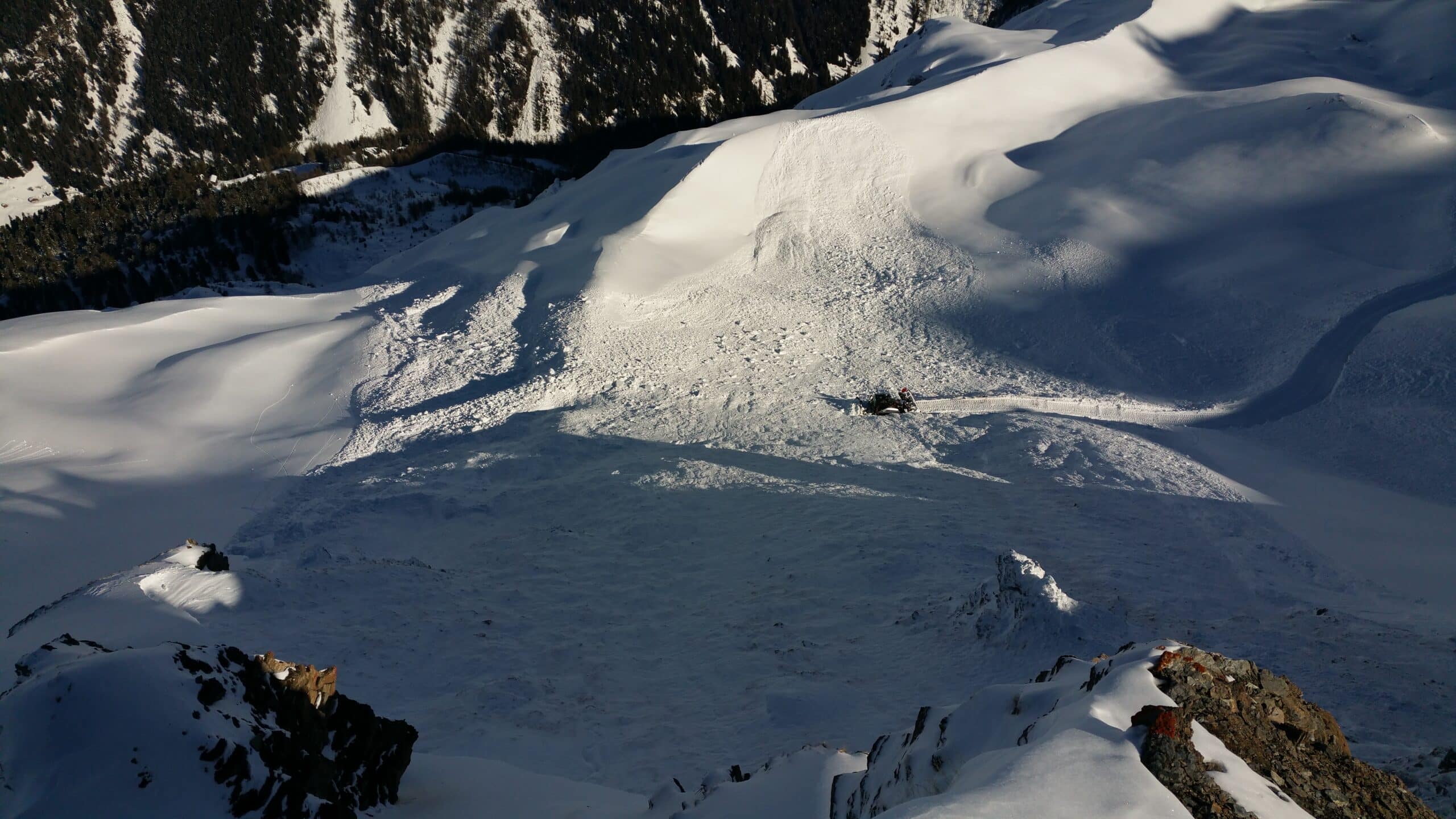 Paysage de montagne enneigé avec avalanche et motoneige.