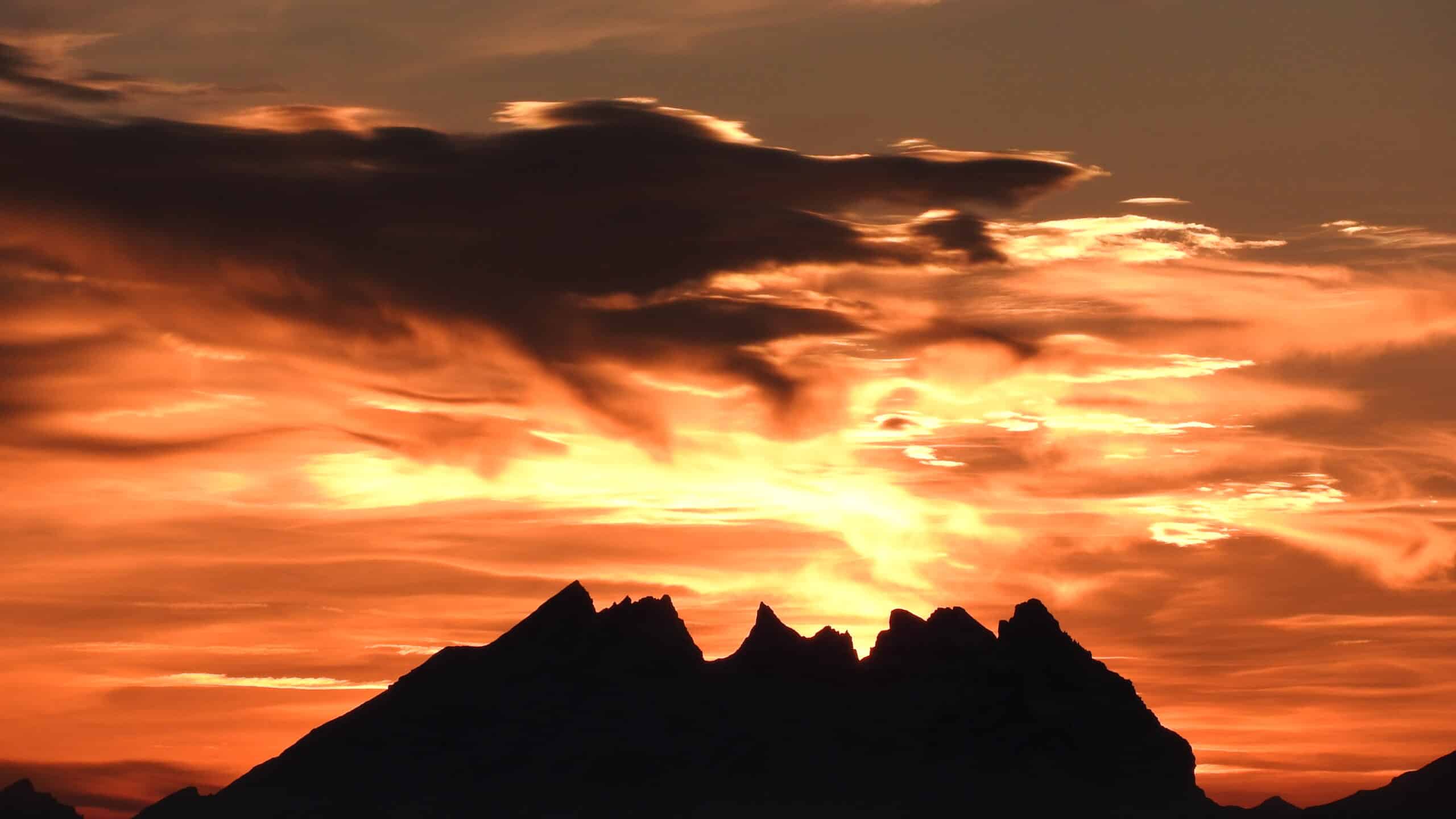 Coucher de soleil intense sur des montagnes sombres.