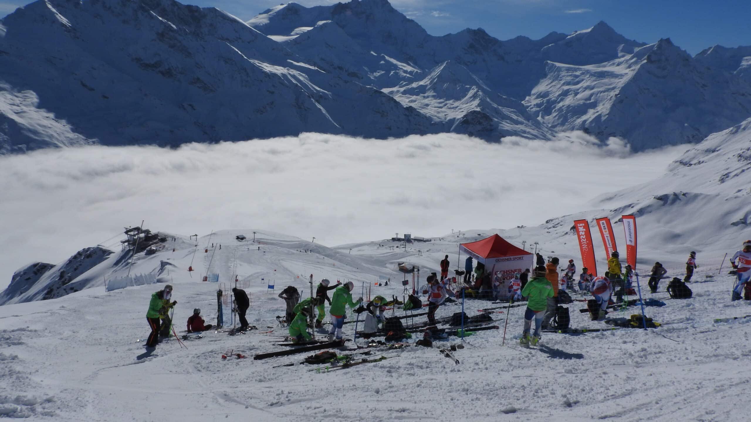 Skieurs sur piste enneigée, montagnes et mer de nuages.