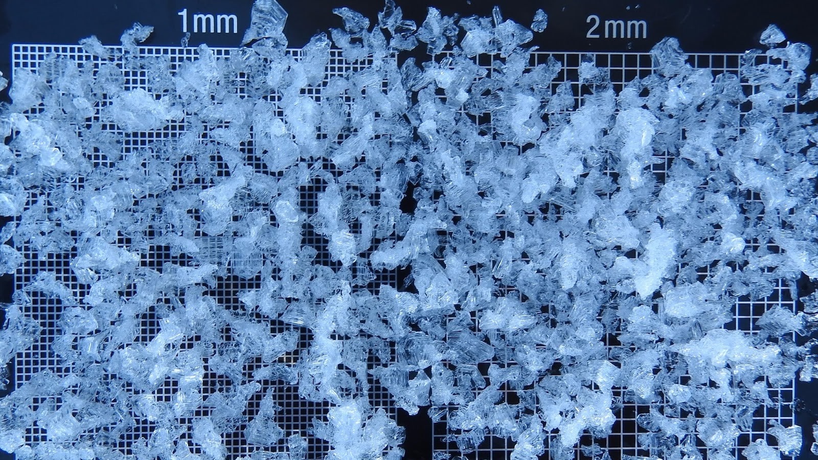 Grains de glace irréguliers sur une grille millimétrée.