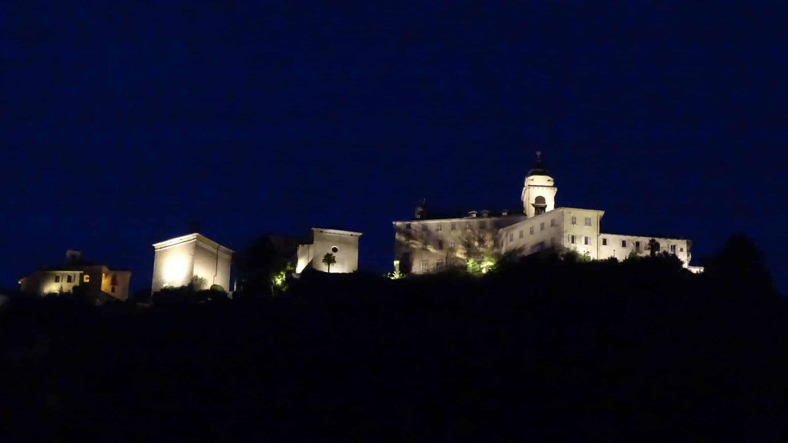 Bâtiments historiques brillamment éclairés sur une colline la nuit.