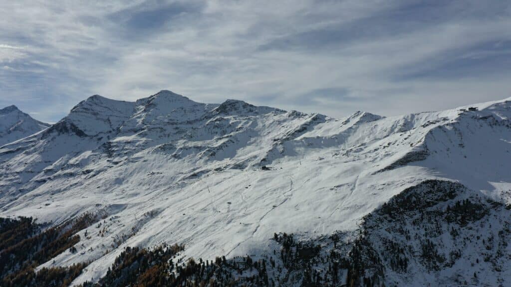 Vue panoramique des montagnes enneigées sous un ciel partiellement nuageux.