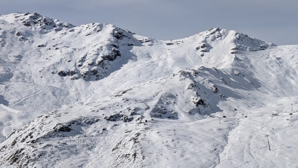 Vue panoramique des montagnes enneigées avec des pentes skiables et des télésièges, capturée en plein hiver.