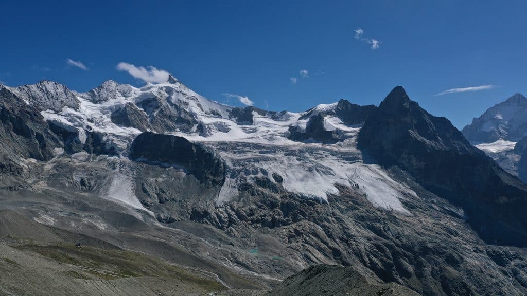 Majestueux paysage alpin avec glaciers, sommets enneigés et ciel bleu.