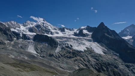 Majestueux paysage alpin avec glaciers, sommets enneigés et ciel bleu.