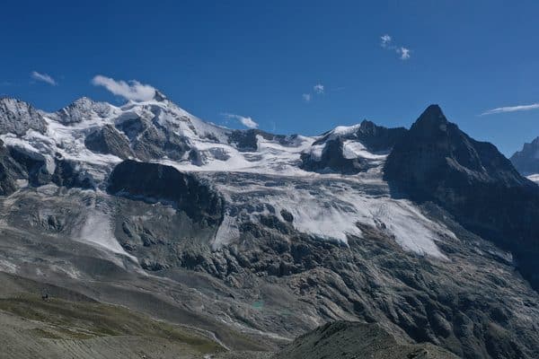 Majestueux paysage alpin avec glaciers, sommets enneigés et ciel bleu.