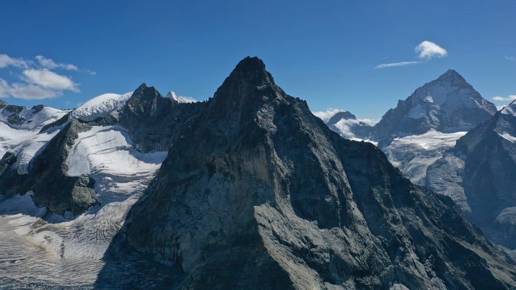 Majestueuses montagnes alpines, sommets rocheux, glaciers et ciel bleu.