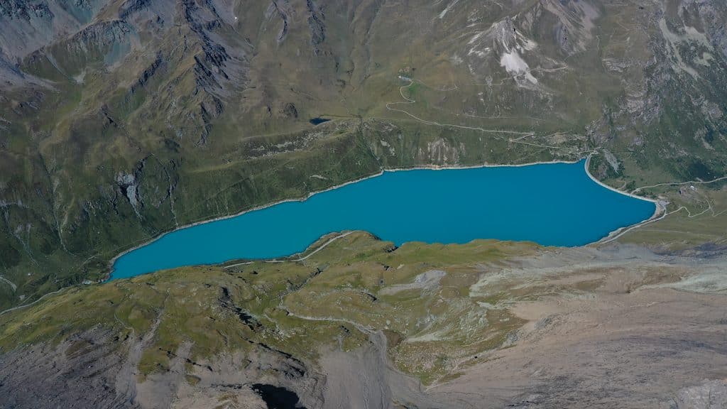 Vue aérienne d'un lac de barrage turquoise dans les montagnes.