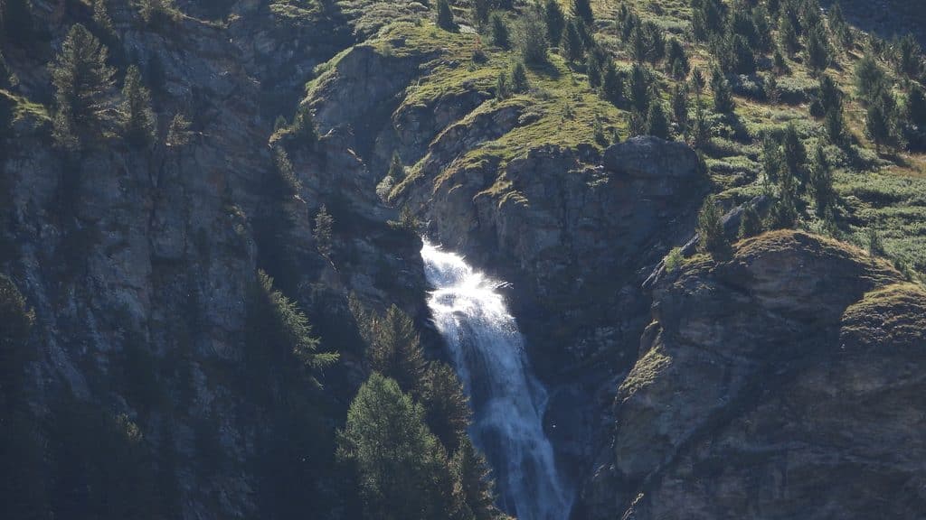 Chute d'eau scintillante dans les montagnes rocheuses couvertes d'arbres.