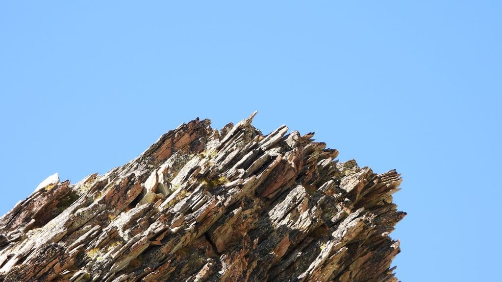 Formation rocheuse stratifiée et escarpée sous ciel bleu.