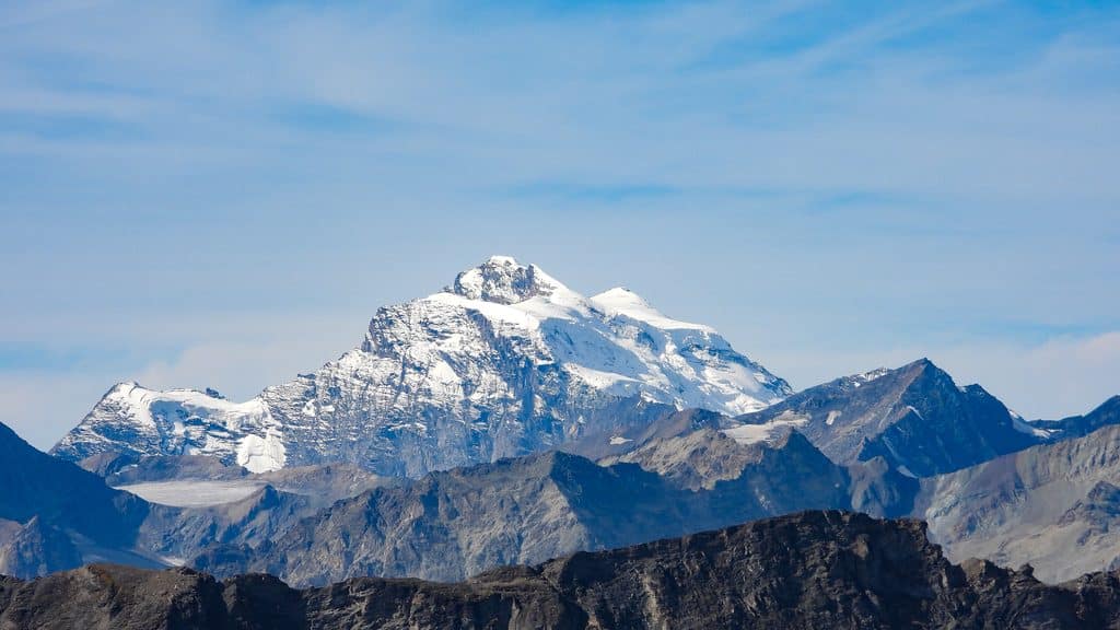 Sommet montagneux enneigé imposant sous un ciel bleu clair.