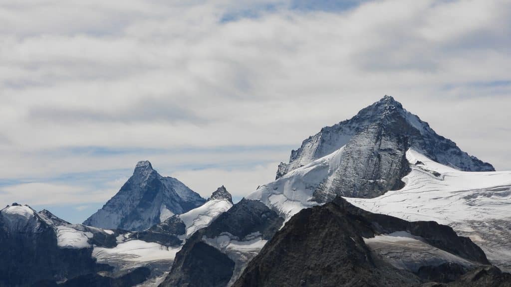 Montagnes enneigées, glaciers alpins sous un ciel nuageux.