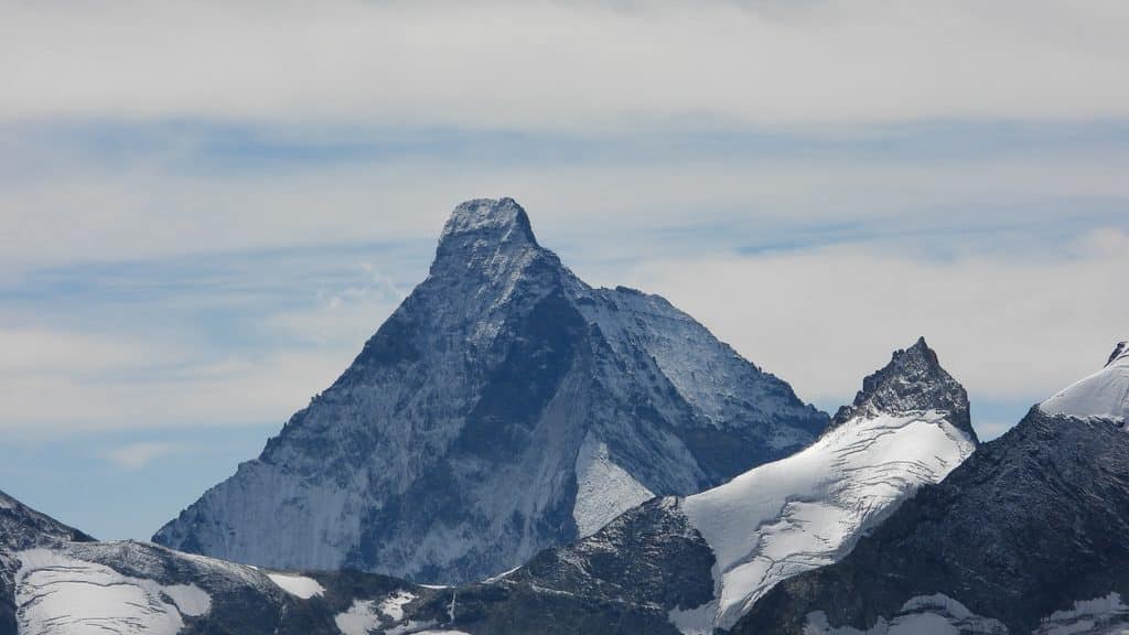 Cervin enneigé, montagnes alpines et ciel nuageux.