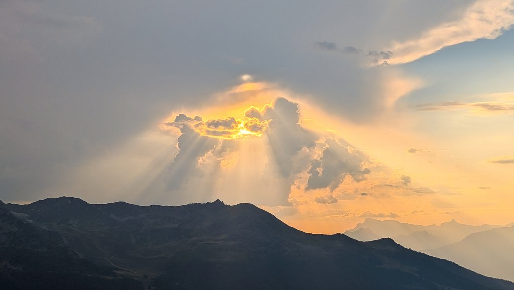 Coucher de soleil spectaculaire avec rayons lumineux sur montagnes.