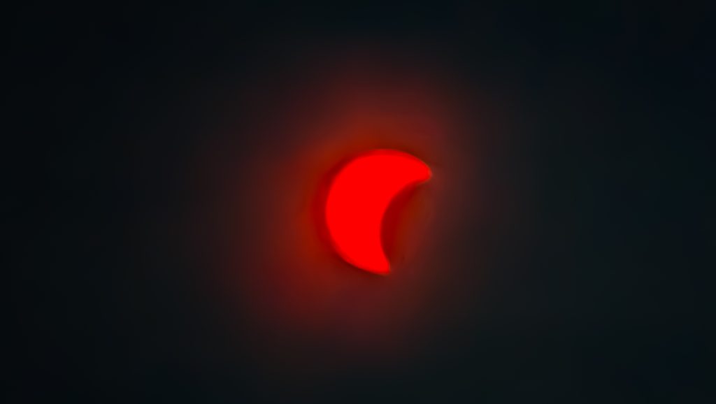 Lumière rouge en forme de virgule sur fond sombre.