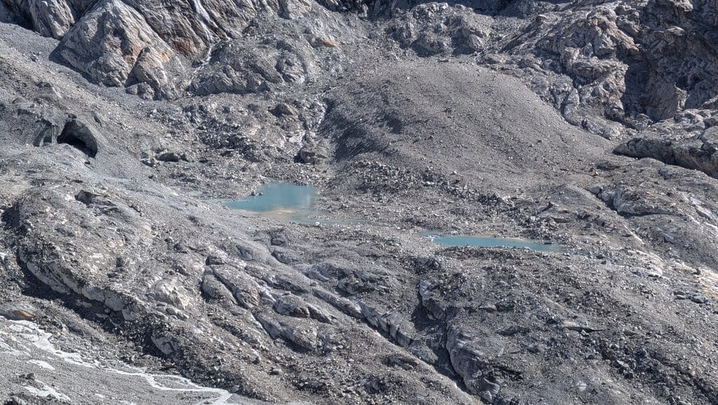 Paysage montagneux rocheux avec lacs glaciaires turquoise et caverne.