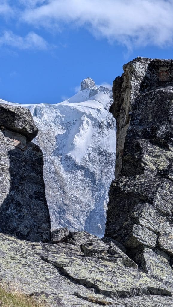 Montagne enneigée encadrée par rochers, ciel bleu lumineux.