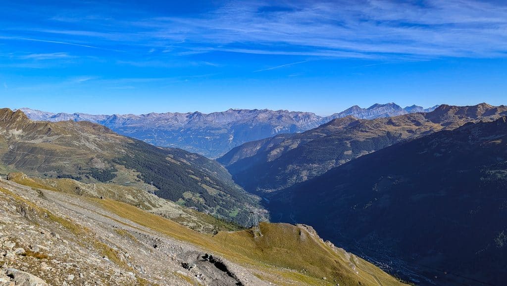 Vue alpine spectaculaire sur une vallée verdoyante et des montagnes escarpées.