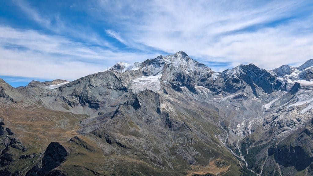 Montagnes majestueuses, sommets enneigés, glaciers, ciel bleu nuageux.