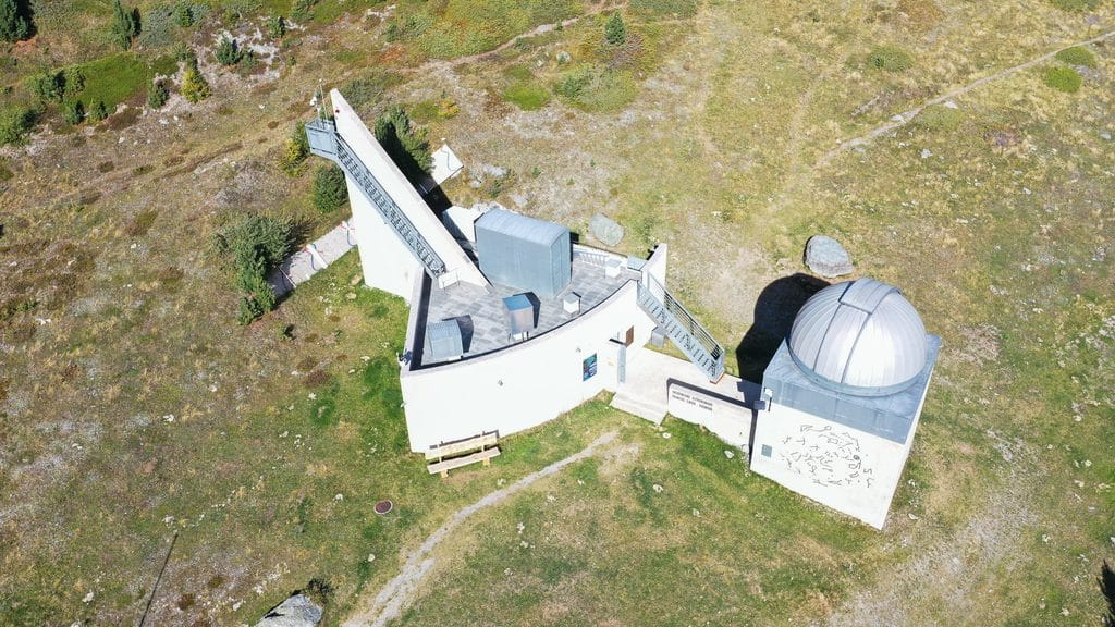 Observatoire astronomique en montagne, télescope solaire et dôme, vue aérienne.