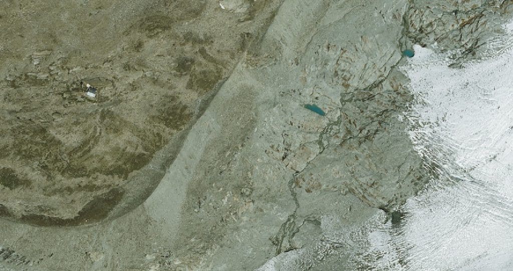 Vue aérienne montagneuse, glacier, lacs et refuge alpin.