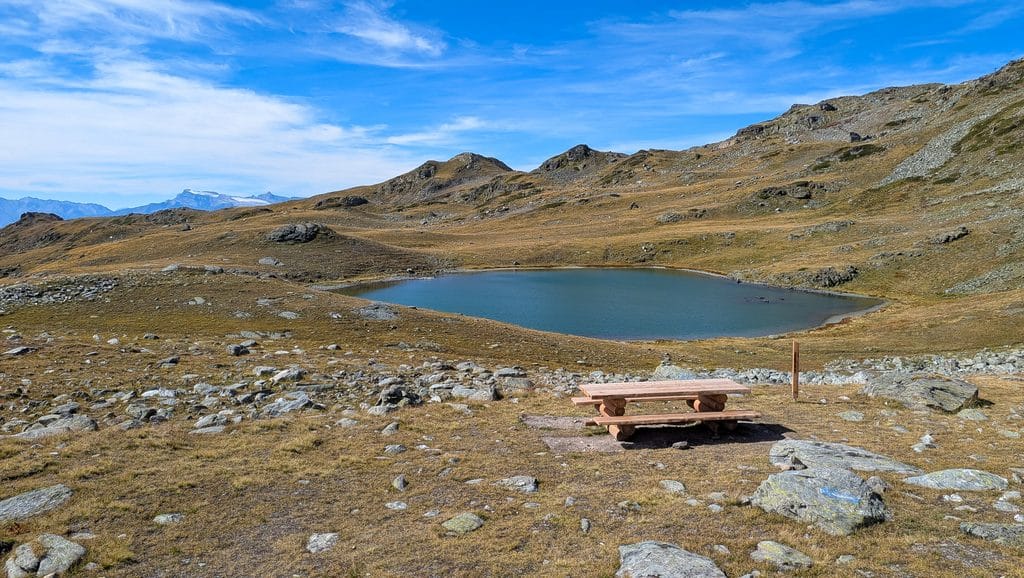 Lac de montagne avec table de pique-nique sous ciel bleu.